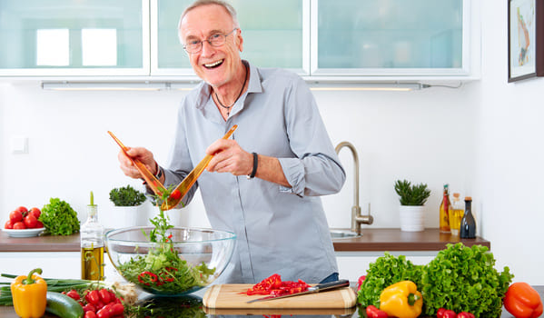 Ein Mann macht sich in der Küche einen Salat.