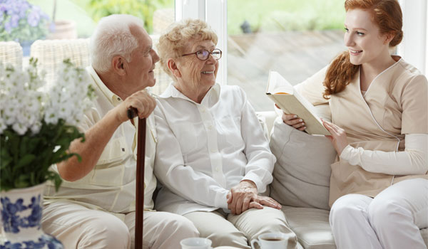 Alltagsassistentin liest Seniorenpaar aus einem Buch vor