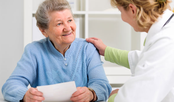 Eine Seniorin erhält eine Verordnung auf Unterstützungspflege von Ihrer Ärztin.