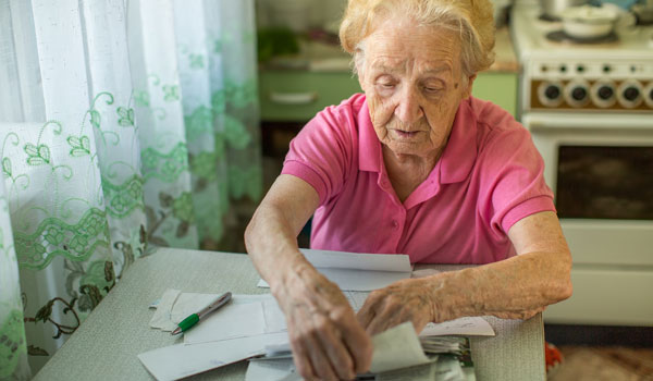 Eine ältere Frau sotiert in der Küche ihre Unterlagen und Papiere.