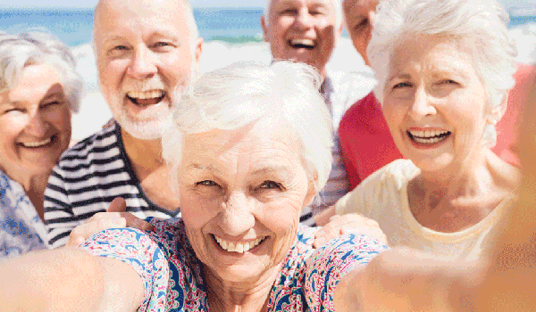 Mehrere Senioren am Strand machen ein Selfie.