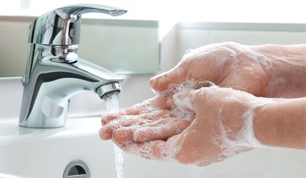 Ein Mensch wäscht sich unter einem fließenden Wasserhahn die Hände.
