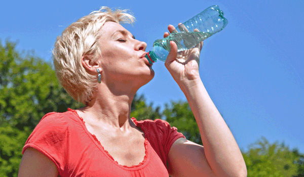 Eine Frau trinkt bei sommerlichen Temperaturen aus einer Flasche Wasser.