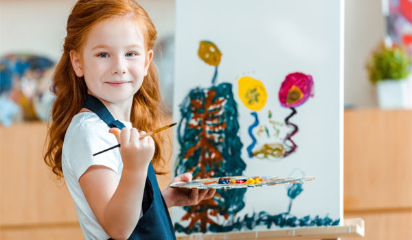 Ein Mädchen mit roten Haaren steht vor einer Leinwand und malt.