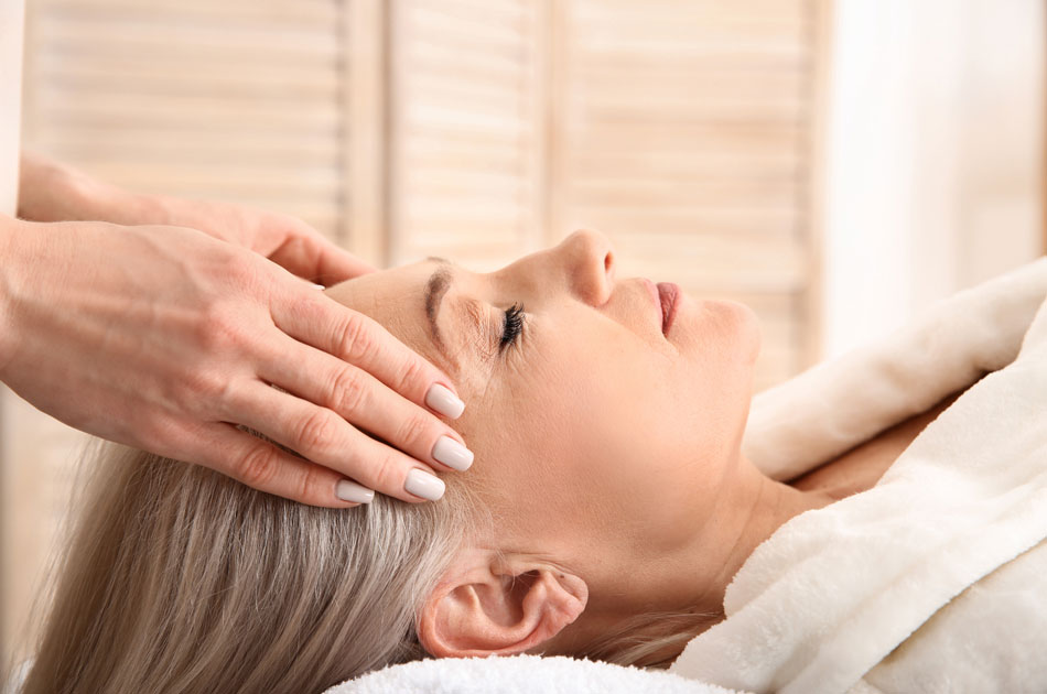 Eine pflegende Angehörige liegt auf einer Massagebank und lässt sich den Kopf massieren.