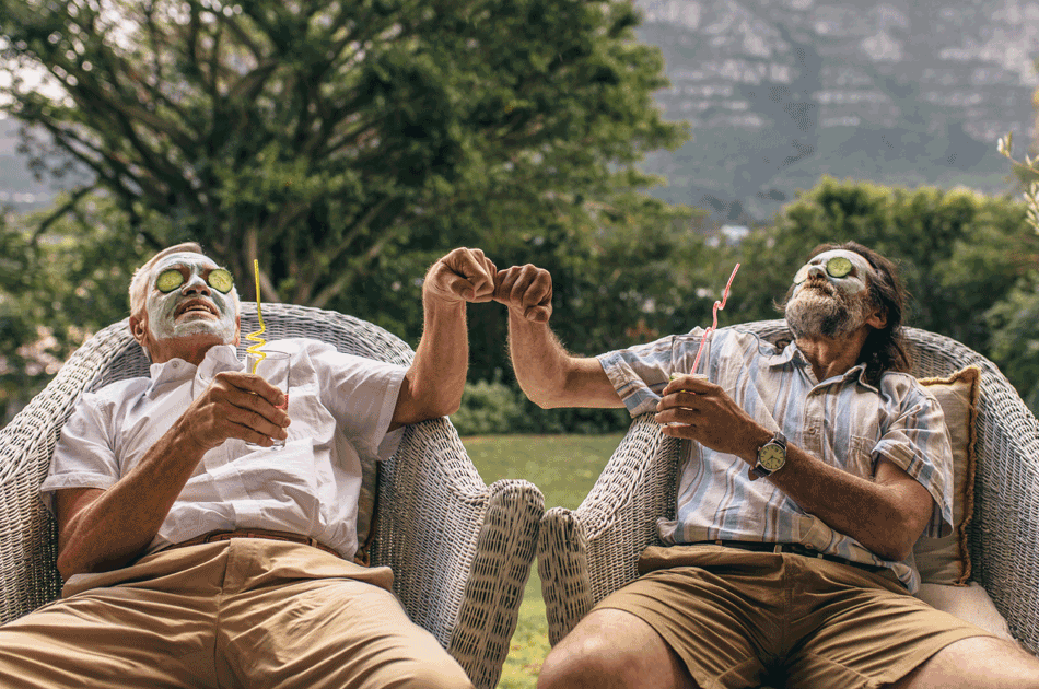Zwei Männer in einem Korbsessel, trinken einen Cocktail und haben Gurkenmasken im Gesicht.