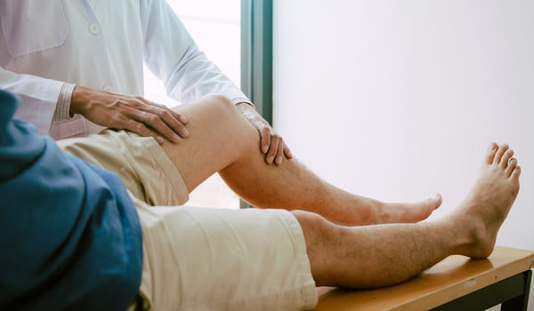 Ein Senior lässt sich beim Arzt sein Bein untersuchen.