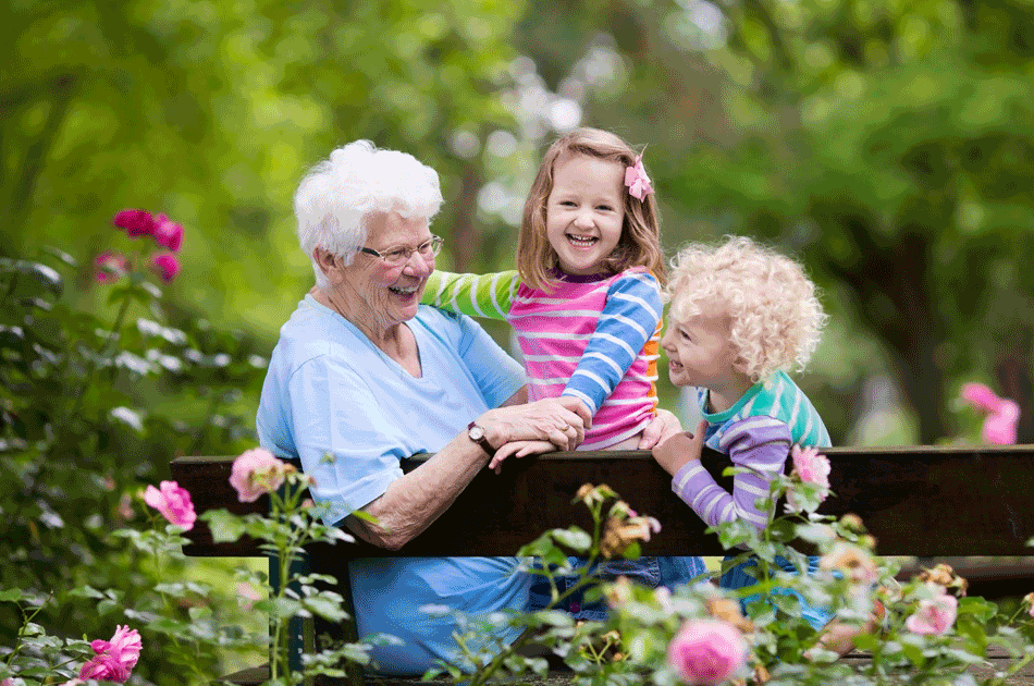 Oma zusammen mit Ihren Enkelkindern auf einer Parkbank.