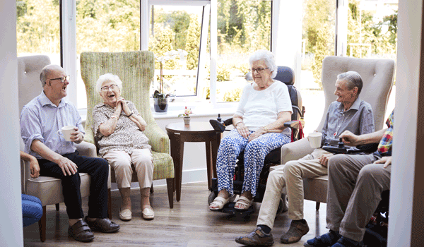 Sechs Senioren sitzen im Sessel und unterhalten sich. 