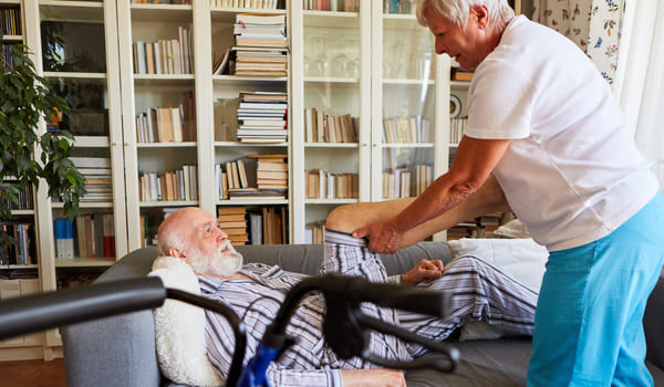 Ein Senior wird zu Hause von einer Physiotherapeutin behandelt.