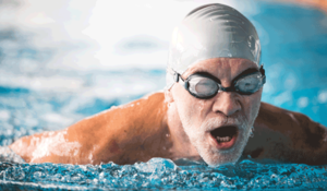 Ein Senior mit Kappe und Schwimmbrille schwimmt in einem Schwimmbecken.