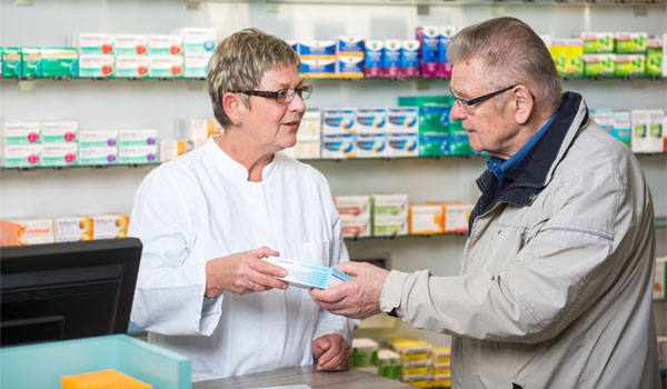 Apothekerin übergibt älteren Herrn sein Medikament