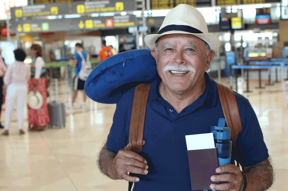 Ein Senior mit Rucksack und Reisepass in einer Flughafenhalle.