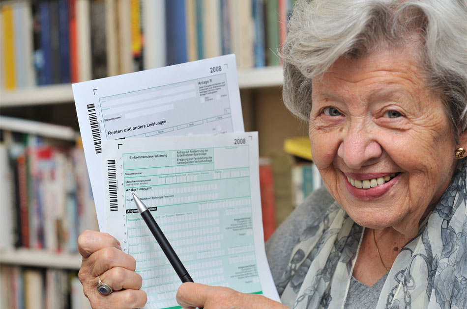 Seniorin hält ein Steuerformular in der Hand.