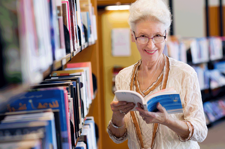 Eine Seniorin in einer Uni Bibliothek.