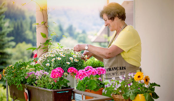 Ein Seniorin pflegt die Blumenkästen auf ihrem Balkon.