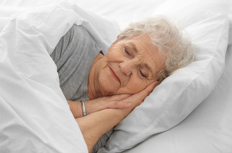 Seniorin liegt im Bett.