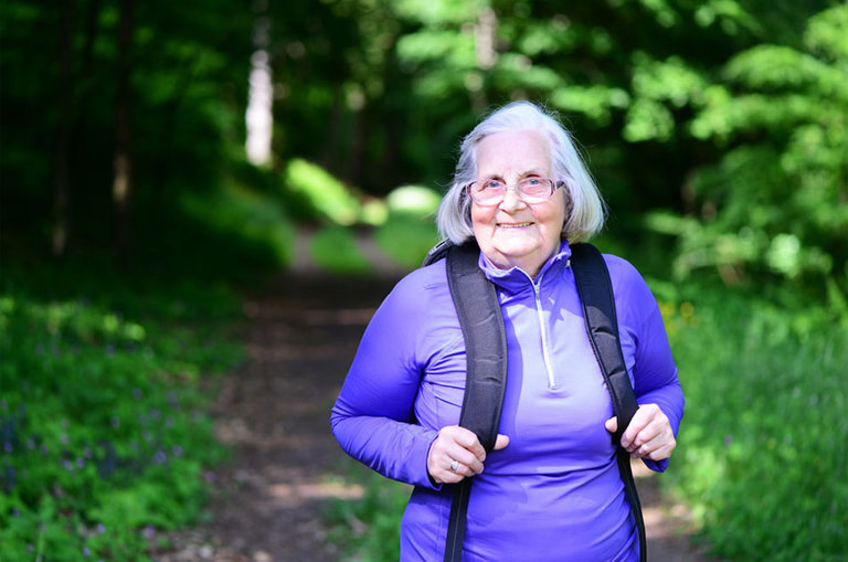 Seniorin unterwegs im Wald beim wandern.