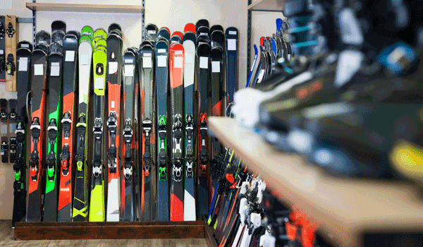 Skiausrüstung wie Skier und Ski-Schuhe in einem Shop, auf zwei Regalen verteilt.