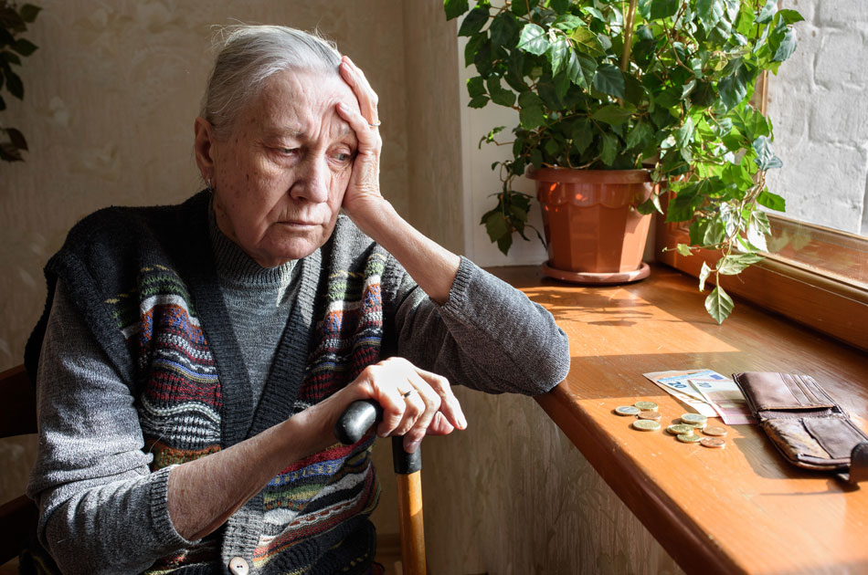 Eine frustrierte Rentnerin sitzt vor ihrer Fensterbank und schaut auf ihre karge Geldbörse, welche nur noch wenig Geld für den Monat enthält.