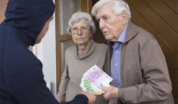Ein Rentnerpaar übergibt einem Trickbetrüger Geld.