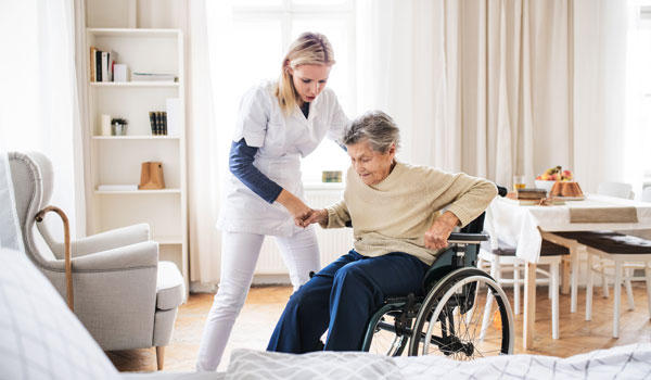 Die Verhinderungspflegerin hilft einer Seniorin aus dem Rollstuhl.