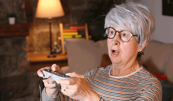Eine Seniorin spielt auf der Couch ein Videospiel.