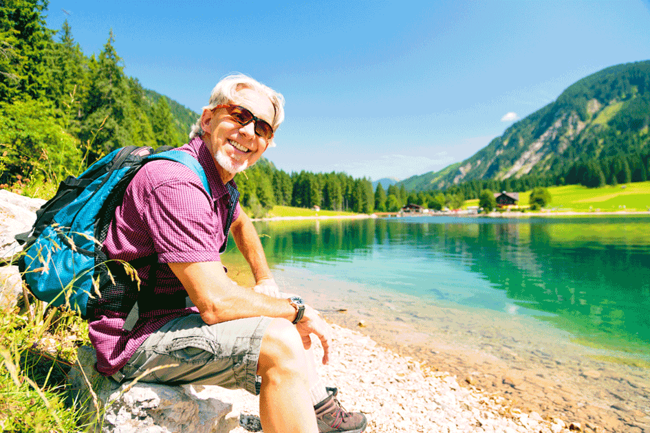 Ein Senior bei einer Wanderung macht Rast an einem Bergsee.