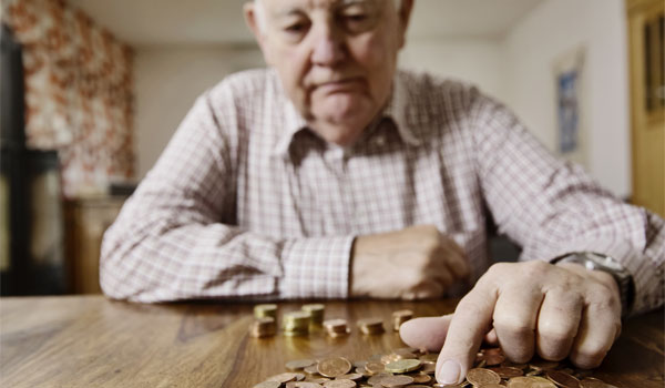 Ein Rentner zählt sein Kleingeld am Küchentisch.