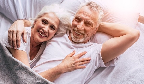 Ein Seniorenpaar liegt im Bett und ist glücklich über die Steuertipps von ProVita.