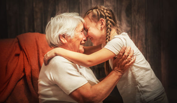 Eine Seniorin nimmt ihre Enkeltochter auf den Arm.