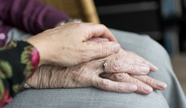 Eine Frau streichelt die Hand ihrer an Demenz erkrankten Mutter.