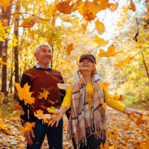 Ein Seniorenpaar spaziert durch einen bunten Herbstwald.