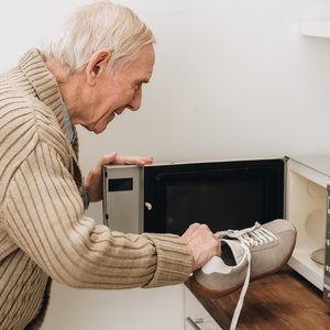 Ein Demenzkranker möchte seine Schuhe in die Mikrowelle legen.