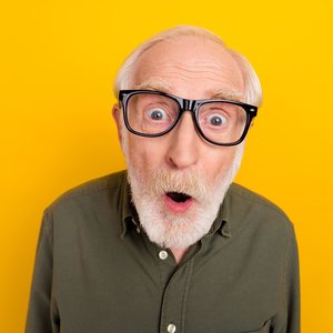 Ein Senior mit Hornbrille blickt erstaunt in die Kamera.