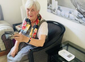 Eine Frau zeigt ihr Hausnotrufgerät.